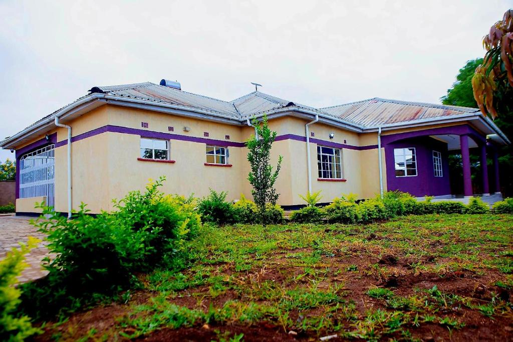 ein Haus mit einem lila Dach in einem Hof in der Unterkunft Sunrise Serenity Lux Homes in Lilongwe