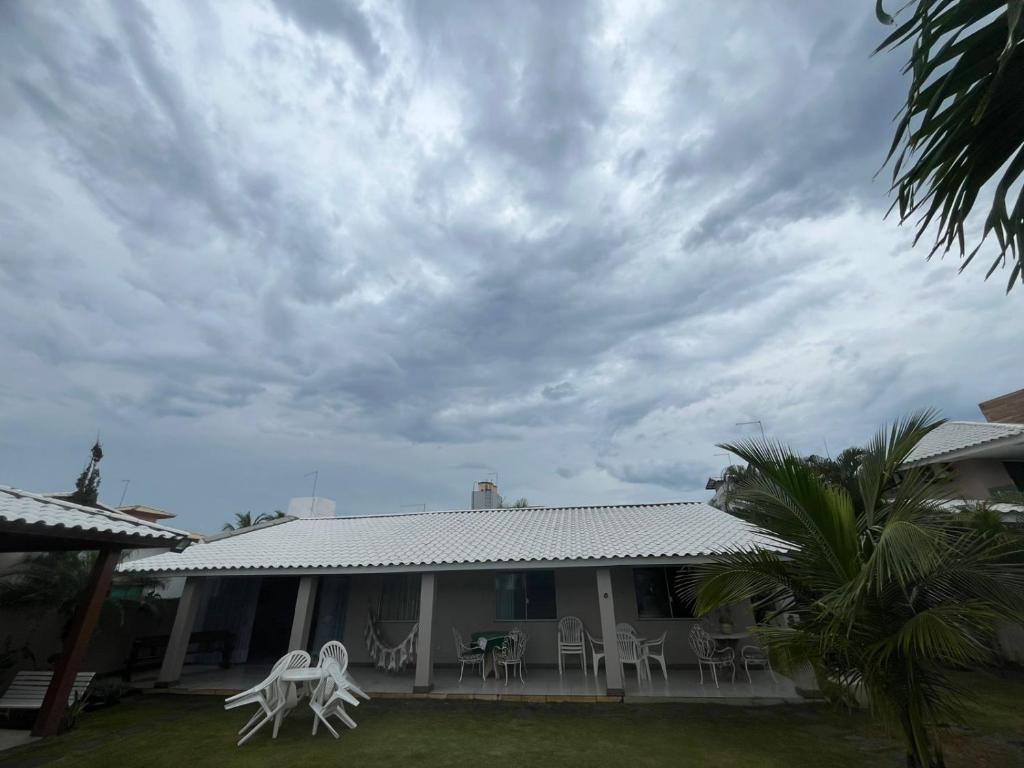 una casa con sedie bianche e un cielo nuvoloso di Casa de Mônica a Camassari