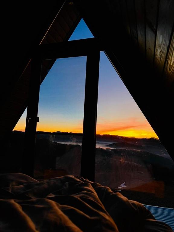a bed in a room with a view of a sunset at A-Frame Retreat Vulcan in Vulcan