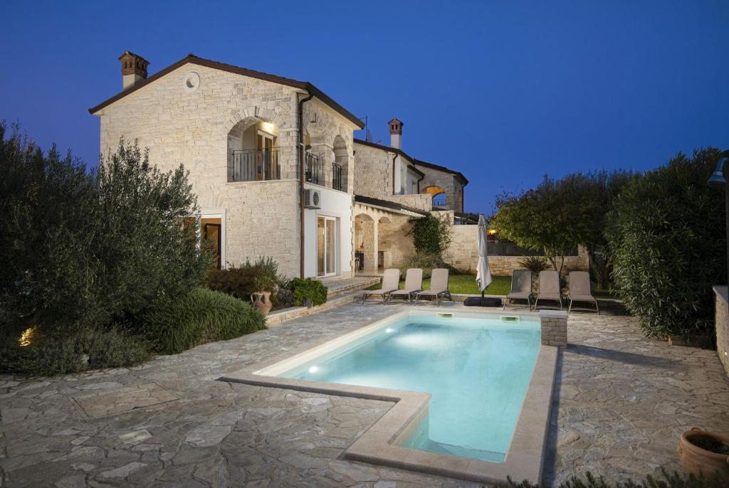 a house with a swimming pool in front of it at Villa Mason with Heated Pool and mini Wellness in Rovinjsko Selo