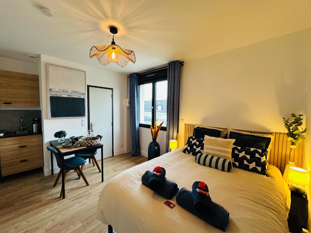 a bedroom with a large bed with a desk and a chandelier at L'Ecume - Le Rheu in Le Rheu