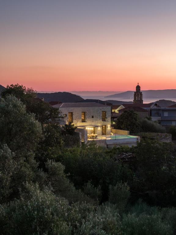 a sunset view of a building with a lighthouse in the background at Terra Maina Villa in Avía