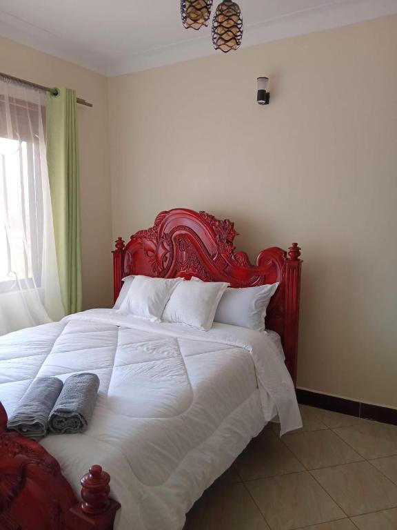 a large bed with a red headboard in a bedroom at Guest House Entebbe Road in Namulanda