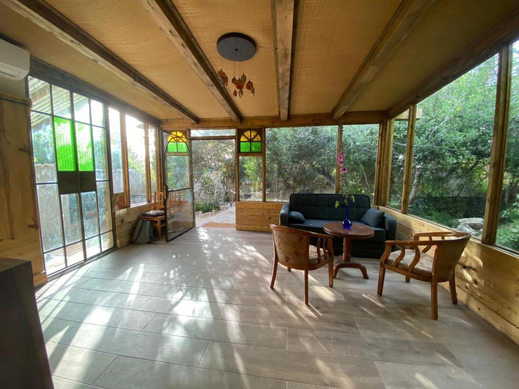 a living room with a couch and a table and chairs at צימר השקדיה in ‘En Hod