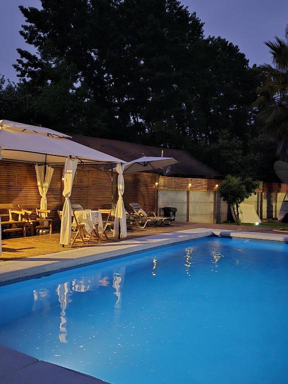 a swimming pool with an umbrella and a table and chairs at Casa Uri in San Fernando