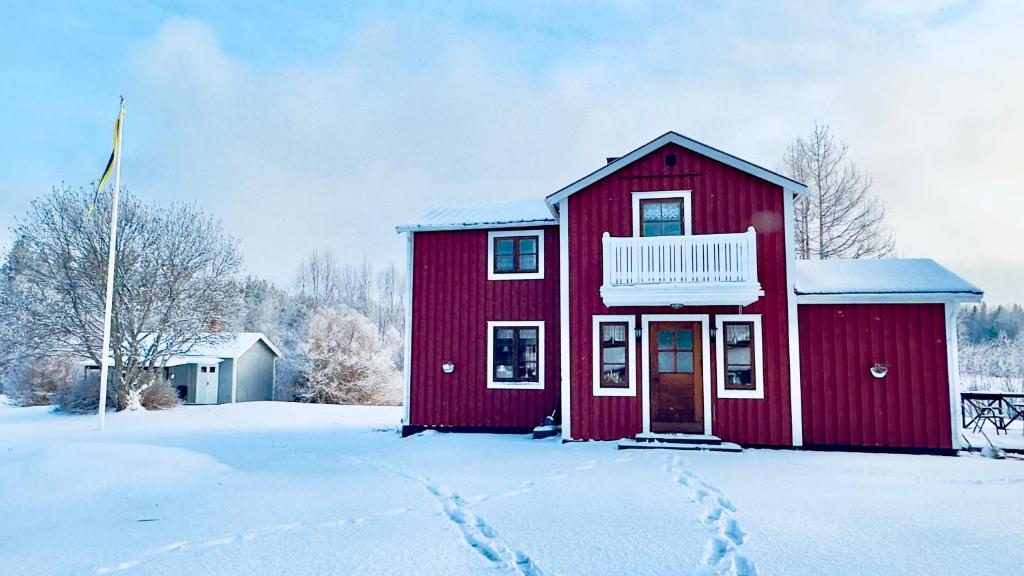 una casa roja con nieve en el suelo en Cozy Family Villa for aurora lovers, en Byske