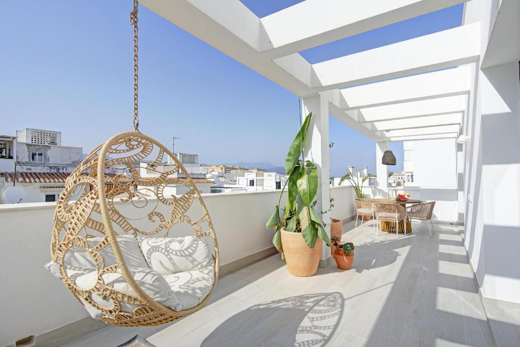 a swinging chair on a balcony with a view at Casa Vega, a un minuto de la playa, PARKING included in Estepona