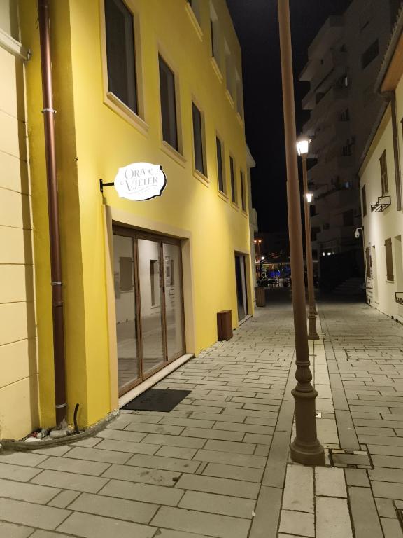 a yellow building with a sign on the door at Ora E Vjeter in Vlorë