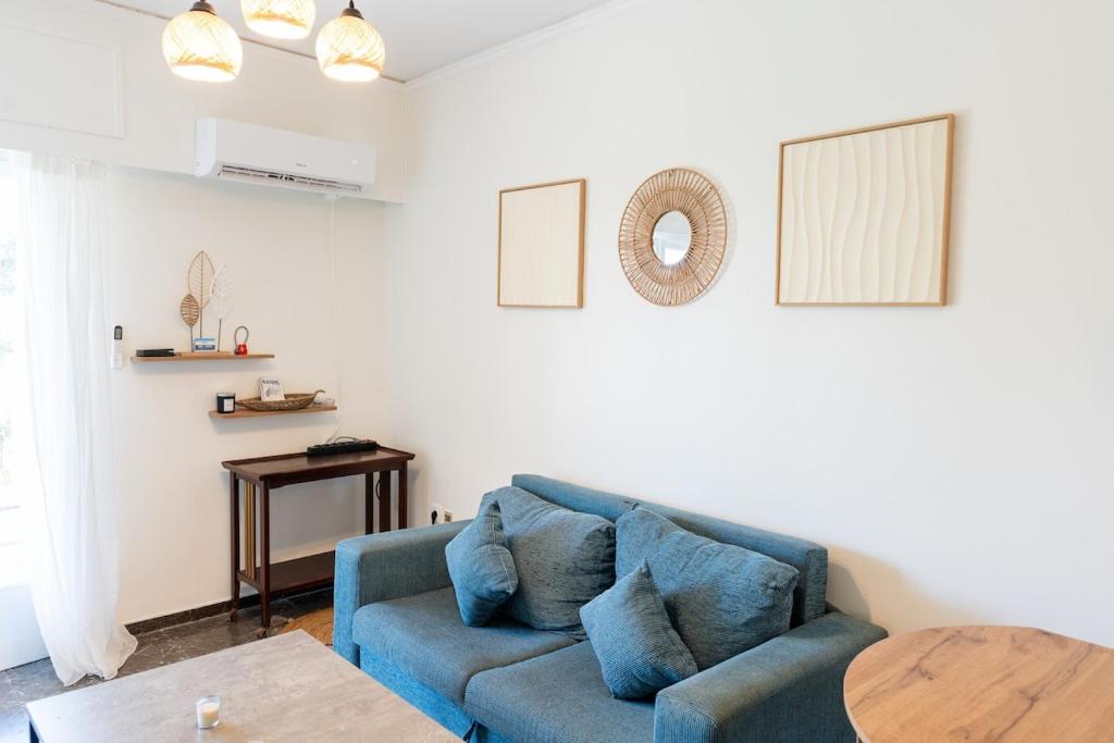 ein Wohnzimmer mit einem blauen Sofa und einem Tisch in der Unterkunft Beachfront Lagonisi Apt 1 Minute From Grand Resort in Kalívia Thorikoú