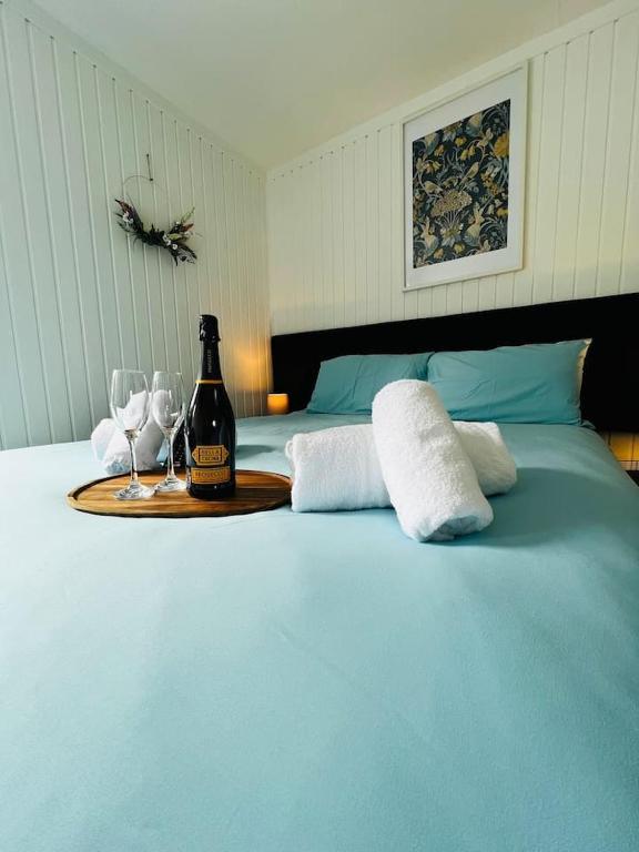 a blue bed with a bottle of wine and two glasses at Tigh Na Mara in Dunoon