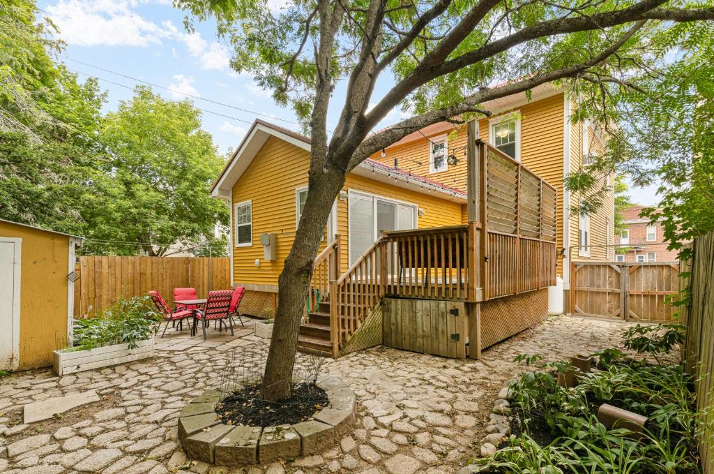 a yellow house with a deck and a tree at Spacious 8 bed stay - HOT TUB, Patio, fireplace, 3 full bathrooms private home in Moncton in Moncton