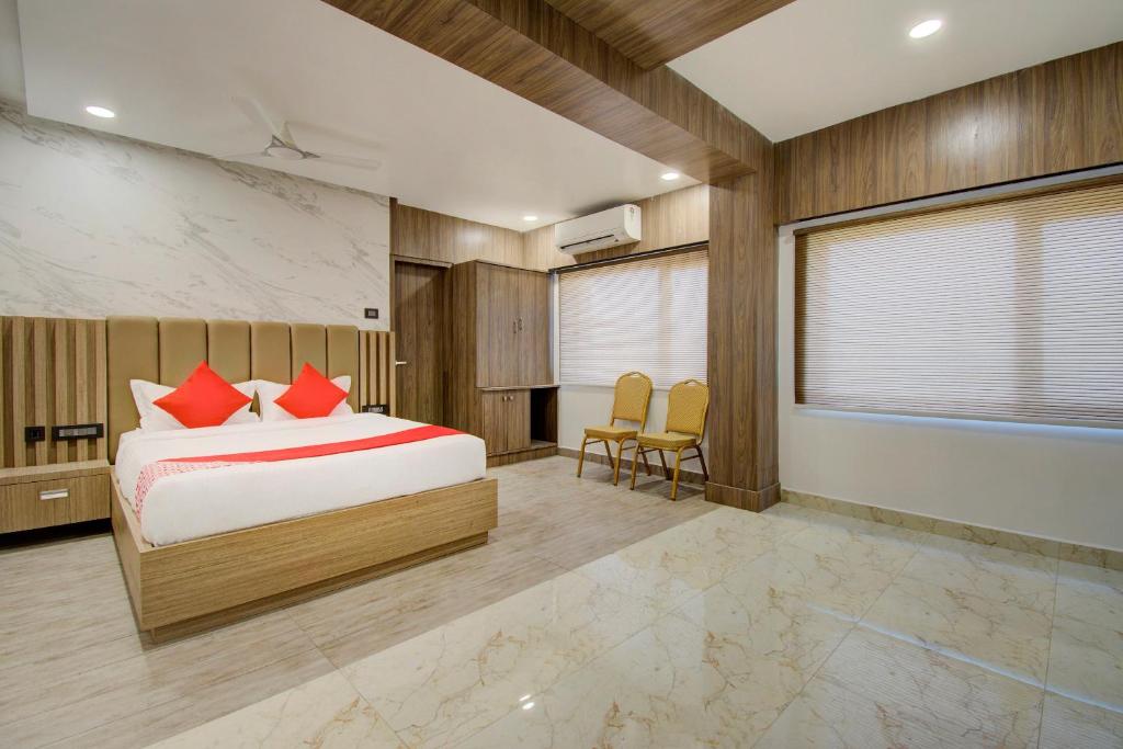 a bedroom with a bed with red pillows at Capital O V Hotel in Vijayawāda