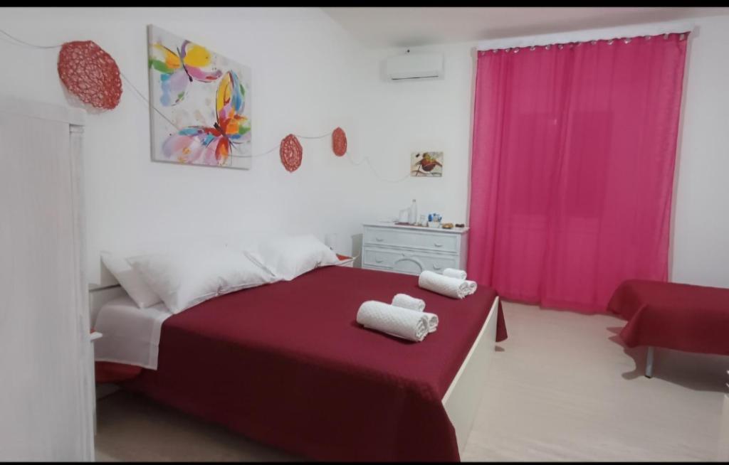 a bedroom with a red bed with a pink curtain at S'apposentu 'e Santa Ruche in Oniferi