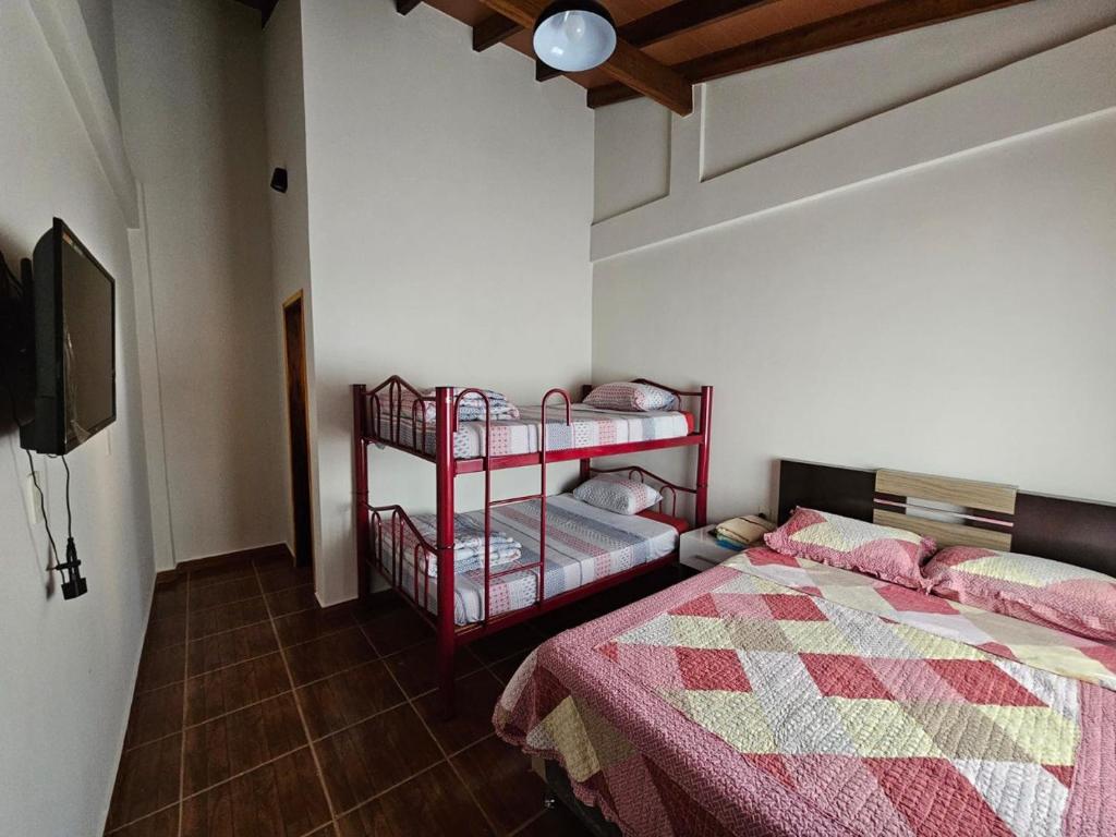 a bedroom with two beds and a tv in a room at MH Hostel in Encarnación