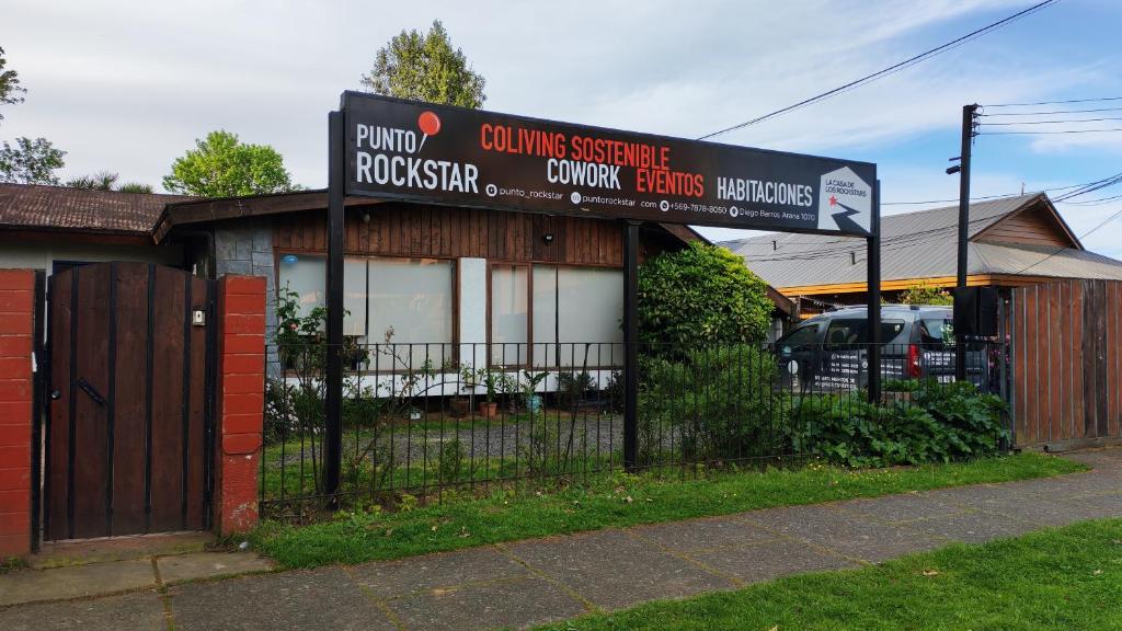 a building with a sign in front of a fence at Hostal Punto Rockstar in Osorno