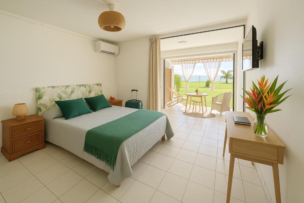 a bedroom with a bed and a patio with a table at Studio le Colibri, Entre terre et mer, vue incroyable, citerne in Le Gosier