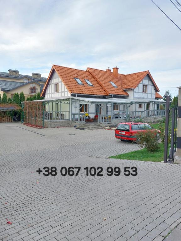 a house with a car parked in front of it at Пансіон АГАВА in Novovolynsʼk