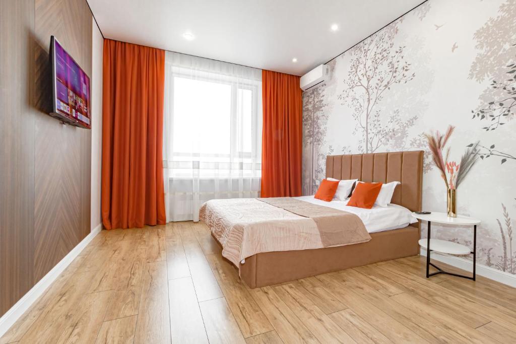 a bedroom with a bed with orange curtains and a window at ALMA PARK Apartments 326 in Taldykolʼ