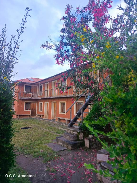 a building with a tree with flowers in front of it at Titicaca Lodge Amantani in Ocosuyo