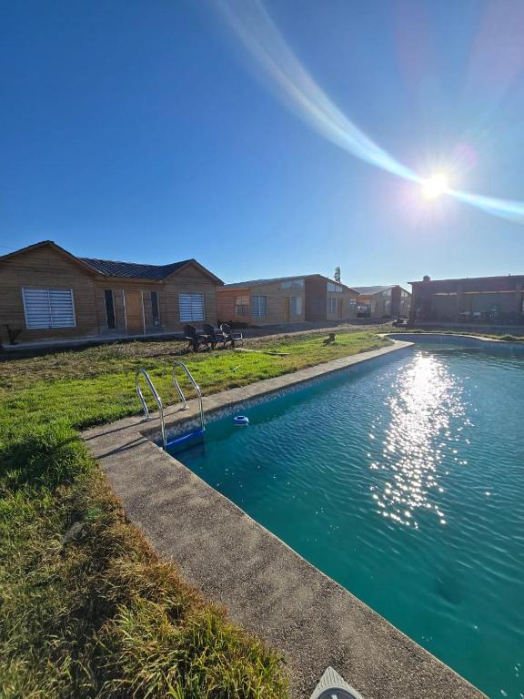 a swimming pool in a yard with the sun shining at Alto La Florida Cabañas in Huasco