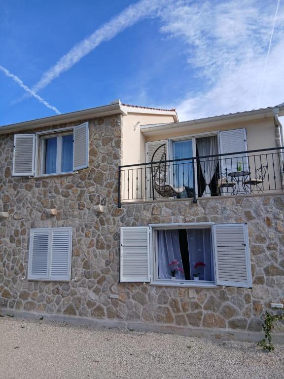 a stone house with white shutters and a balcony at Apartman Lasko 1 in Goveđari