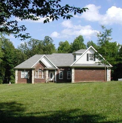 a house on a grassy field with a tree at Copeland Castle in Greensboro