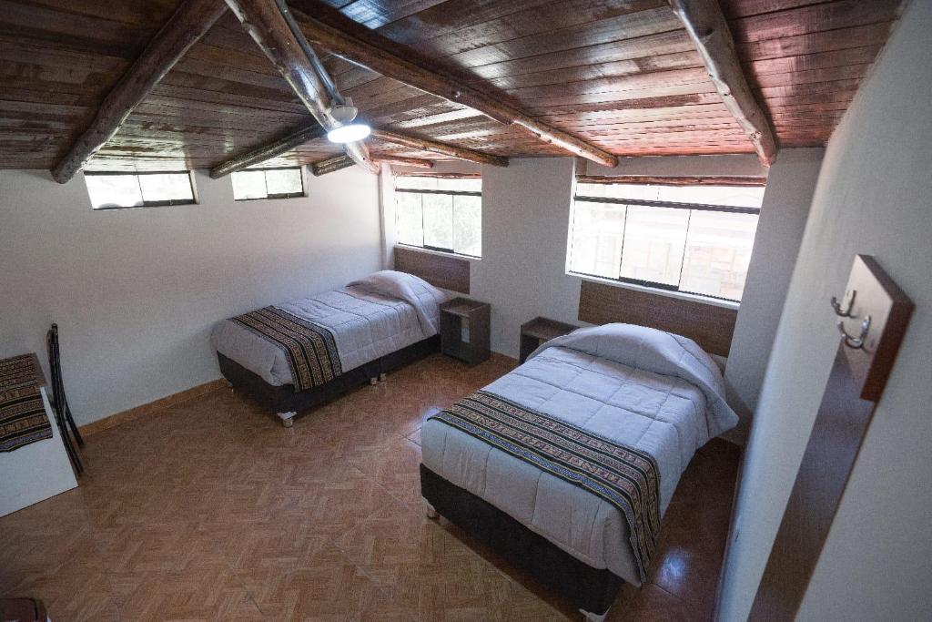 a bedroom with two beds in a room with windows at Refugio Sagrado Boutique Ollantaytambo in Ollantaytambo
