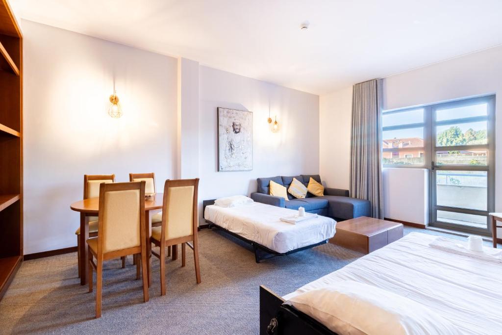 a hotel room with a bed and a dining room at Hotel La Fontaine in Esmoriz