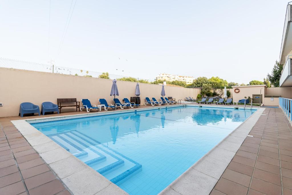 a large swimming pool with blue chairs in a hotel at Hotel La Fontaine in Esmoriz