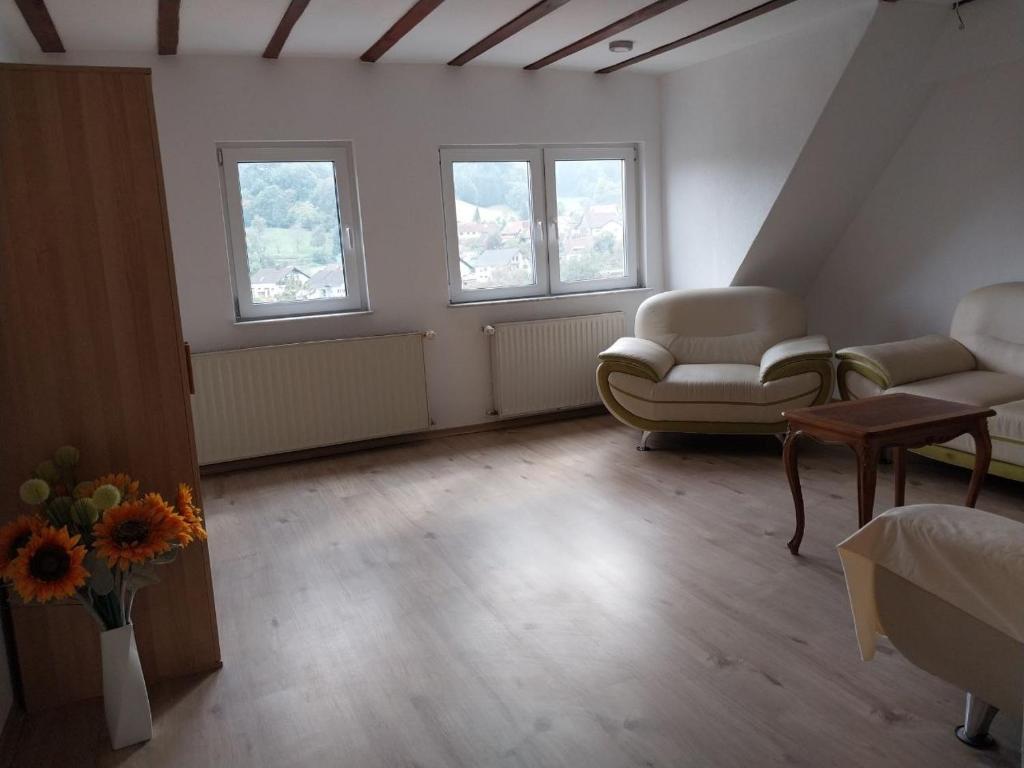 a living room with two chairs and a table and two windows at Waldblick in Hirschhorn in Hirschhorn