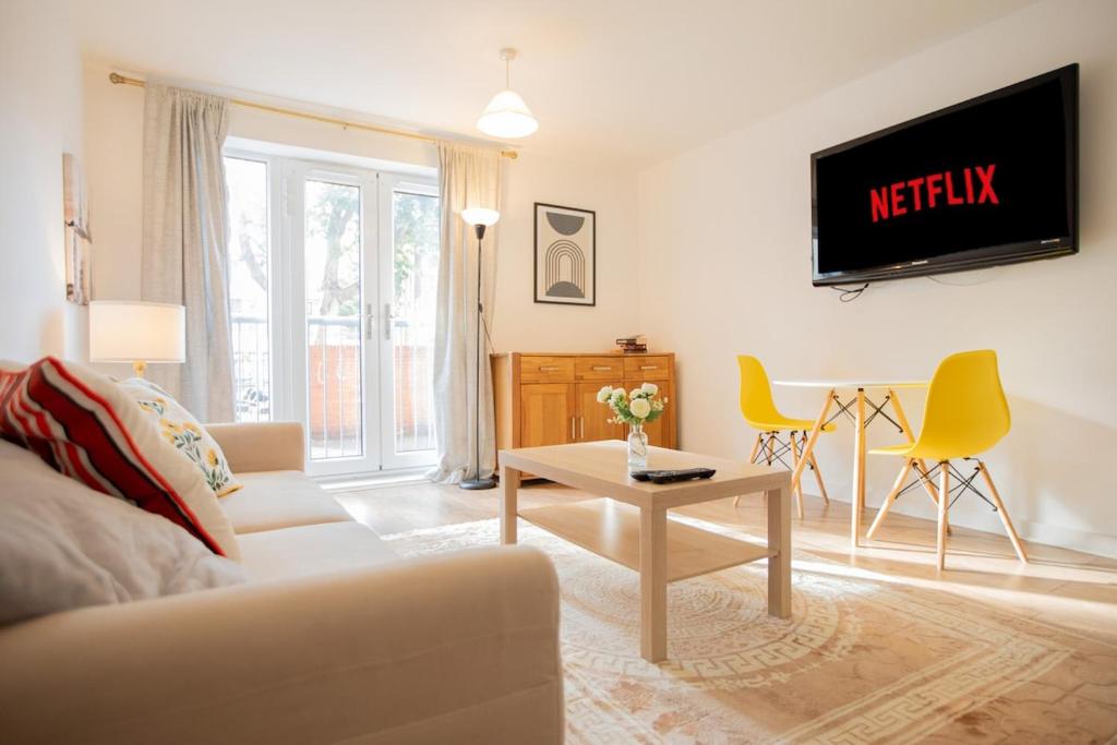 ein Wohnzimmer mit einer Couch und einem Fernseher an der Wand in der Unterkunft Modern 2-Bed Apartment in Central Portsmouth in Portsmouth