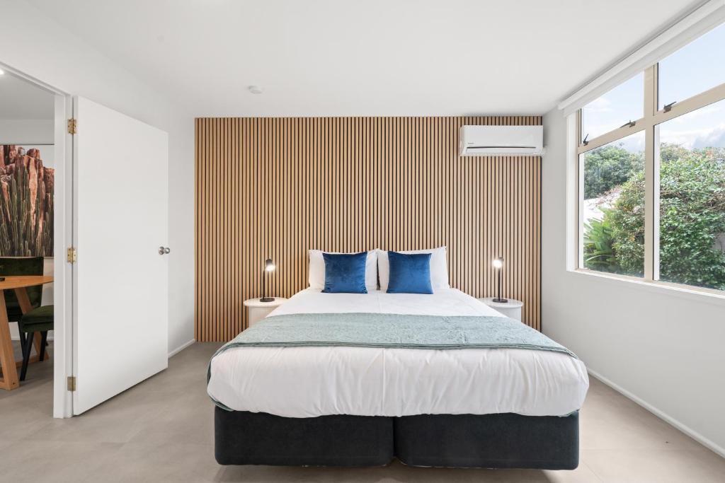 a bedroom with a large bed with blue pillows at Pacific Motor Inn in Mount Maunganui