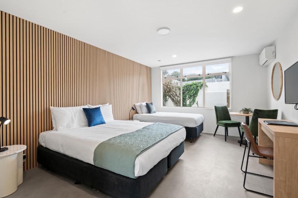 a hotel room with two beds and a desk at Pacific Motor Inn in Mount Maunganui