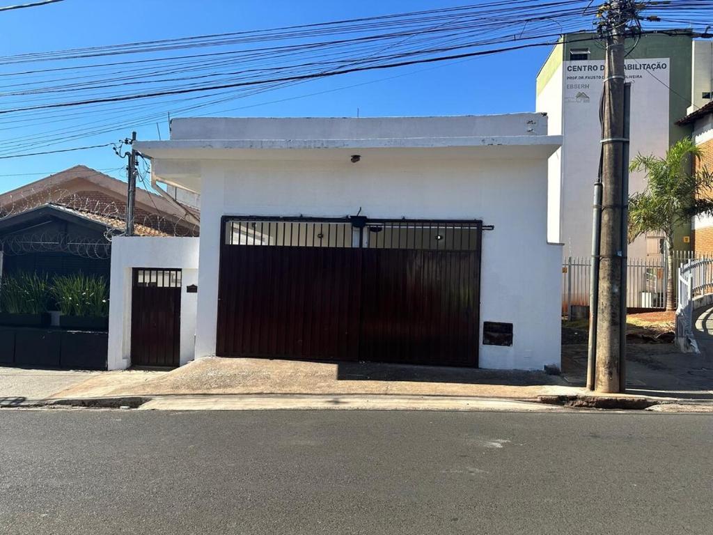 a white house with a black gate on a street at Casa de Vó - Casa Inteira in Uberaba