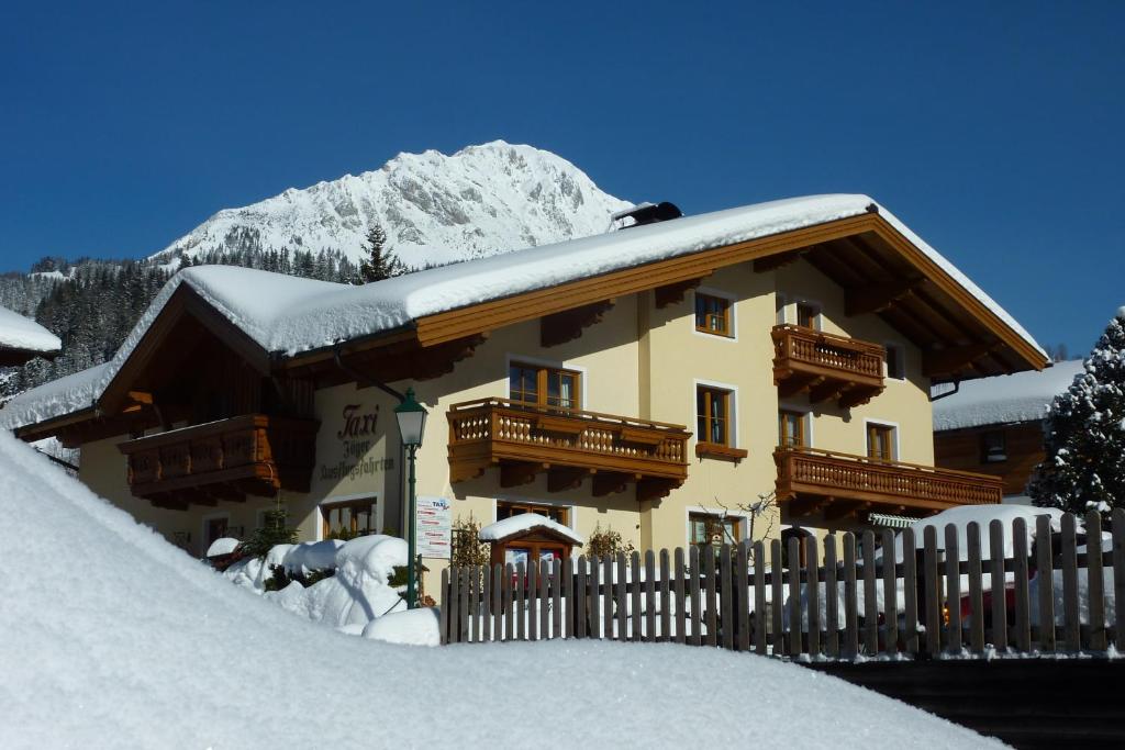 une maison recouverte de neige devant une clôture dans l'établissement Haus Jäger, à Filzmoos