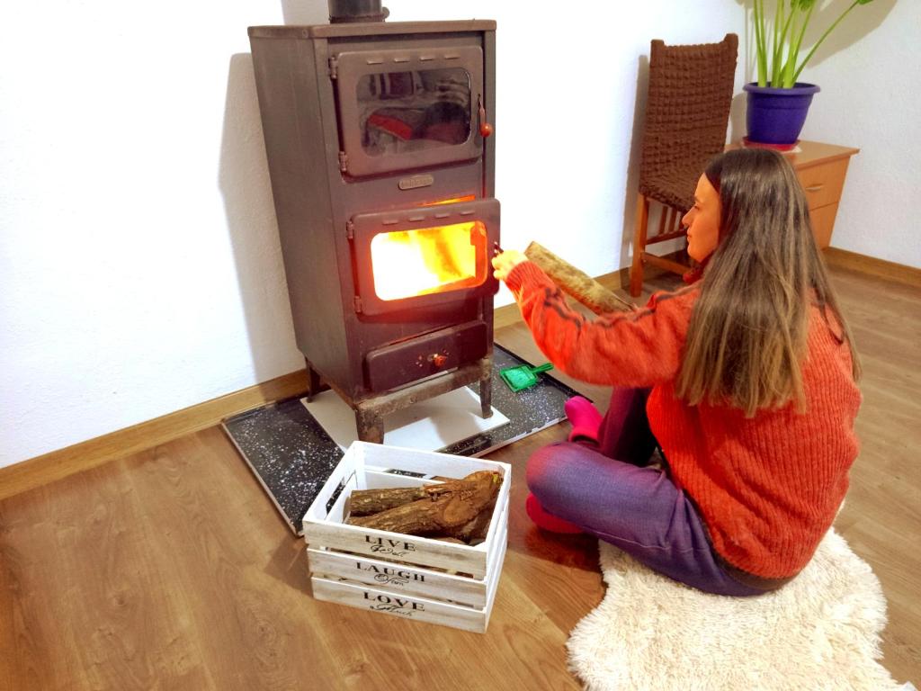 a woman is sitting in front of a stove at Taku Villa Wonderful view of Lake Ohrid in Udënisht