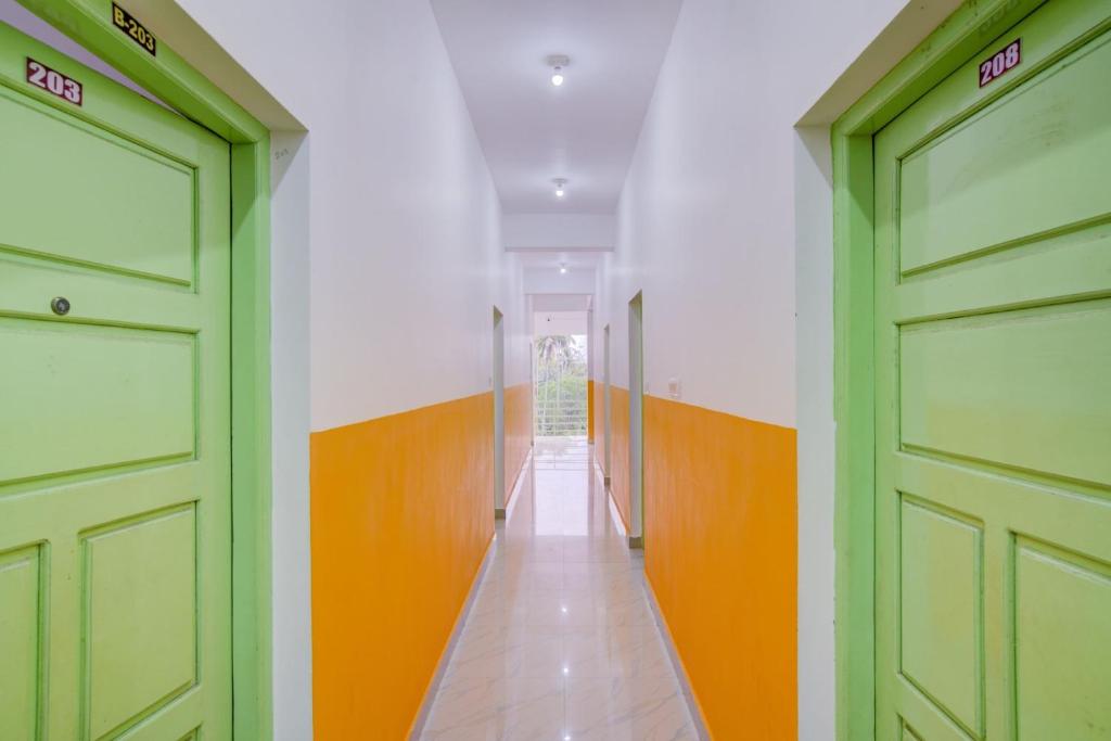 a hallway with green doors and orange and white walls at Hotel O Dream Palace in Kovalam