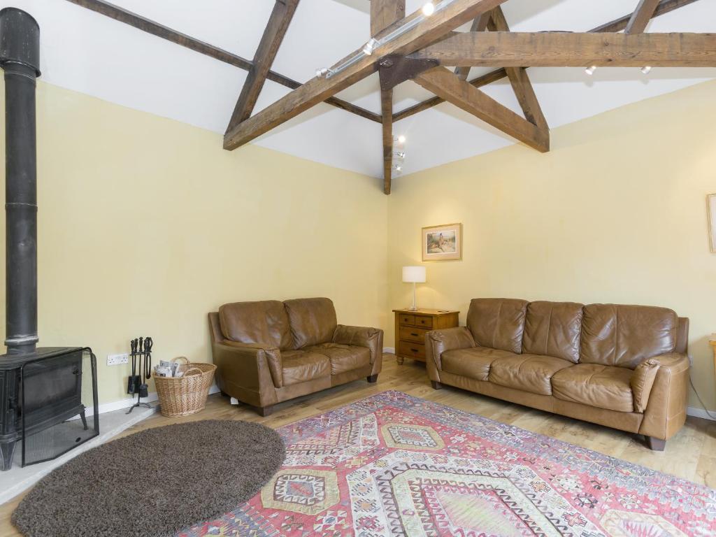 a living room with two leather couches and a fireplace at Ingleby Barn - 27946 in Battersby