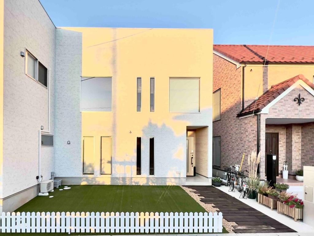 una casa con una valla blanca delante en The Dolphin, en Inzai