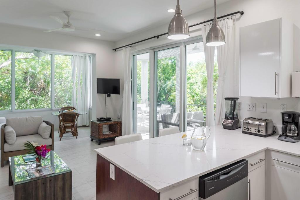 a kitchen and living room with white counter tops and windows at Wyakha 1 Garden View in Long Bay Hills