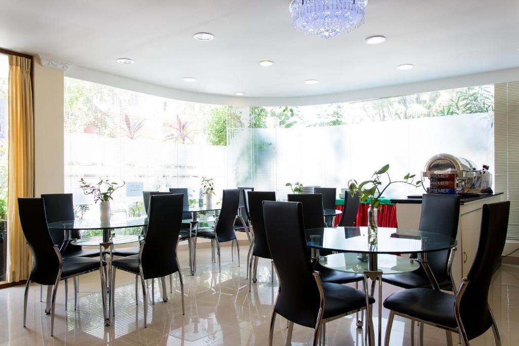 a dining room with glass tables and black chairs at Beach Palace in Hulhumale