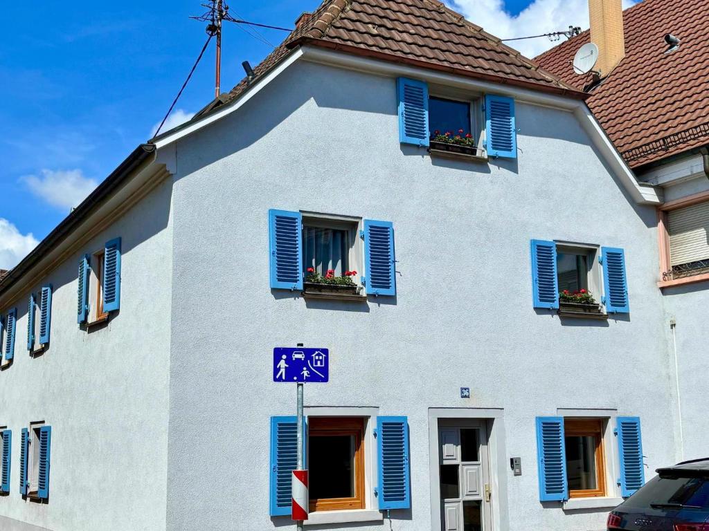 a white building with blue shuttered windows and a street sign at Apartment in Herbolzheim in Herbolzheim