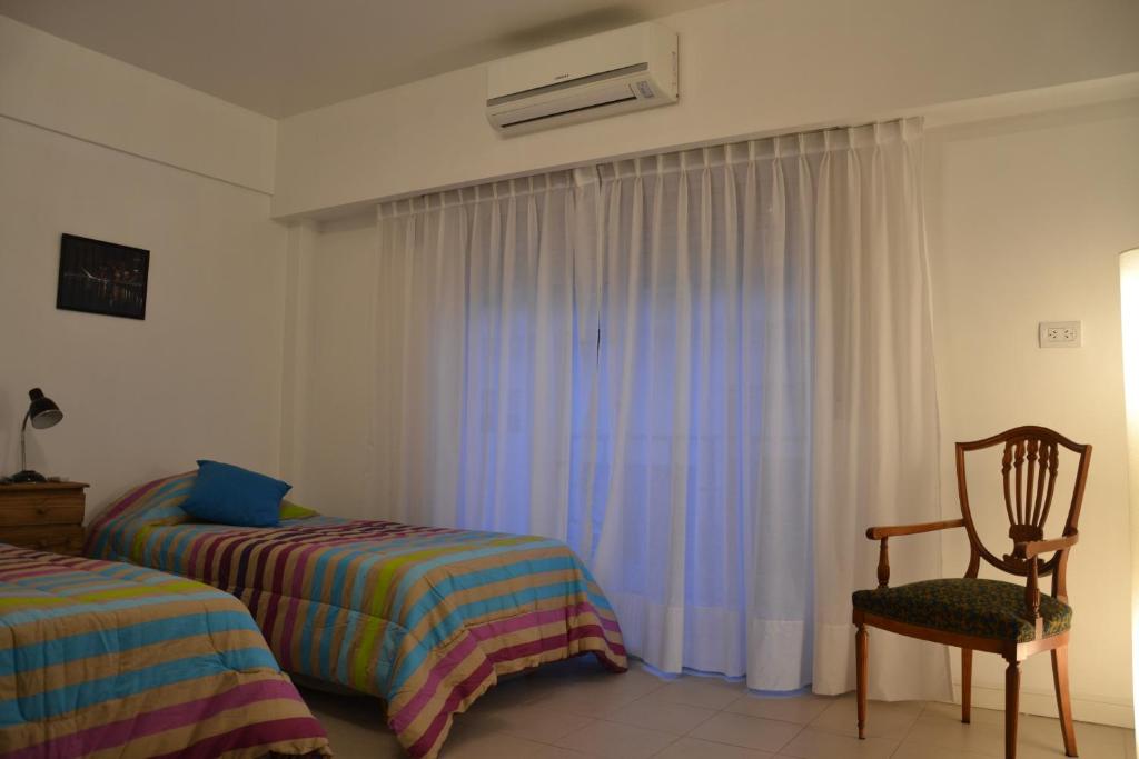 1 dormitorio con 2 camas, silla y ventana en BA Downtown Apartment en Buenos Aires
