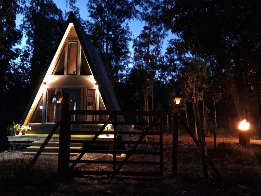 a small cabin with a porch at night at Alpinas del bosque in Sauce de Portezuelo