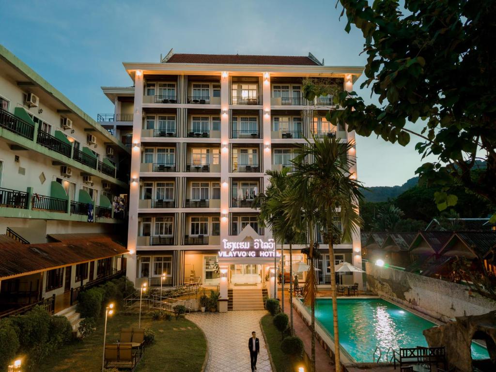 a hotel with a swimming pool in front of a building at Vilayvong Hotel in Vang Vieng