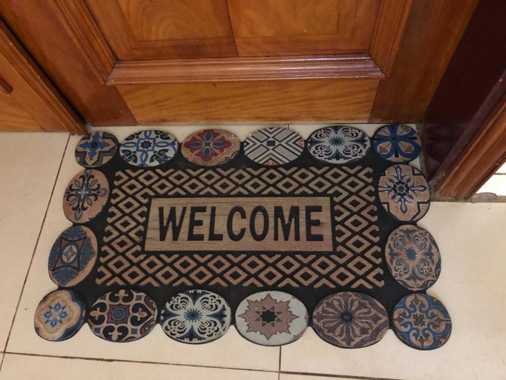 a welcome sign on a tile floor with blue and white plates at Grand Appartement à essos mobile in Yaoundé