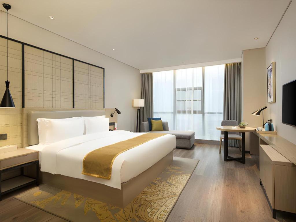 a hotel room with a large bed and a desk at Echarm Hotel Changsha Gaoqiao in Changsha