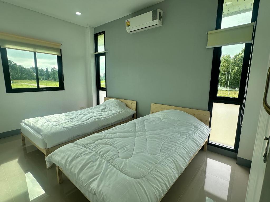 two beds in a room with two windows at Healstay Hostel in Nan