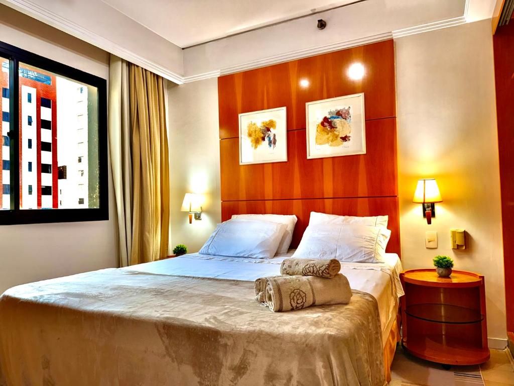 ein Schlafzimmer mit einem großen Bett mit einem hölzernen Kopfteil in der Unterkunft Flat em Hotel de Luxo MercPrivilege - 5 Min do Aeroporto in São Paulo