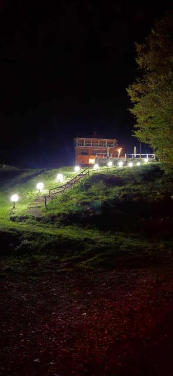 a building on top of a hill at night at Cabana Cerbu in Bozovici